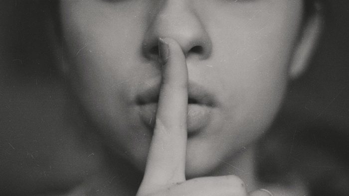 Person holding finger to lips