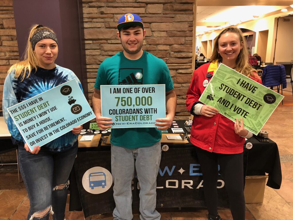 Three students hold up photo petitions in support of legislation tackling the student debt crisis