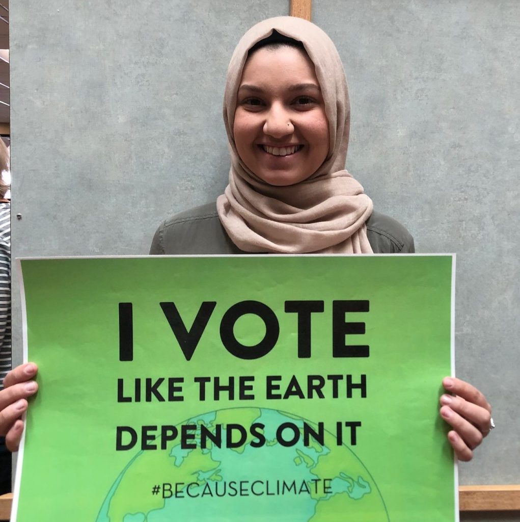 Student holds up a photo petition that says "I vote like the earth depends on it"